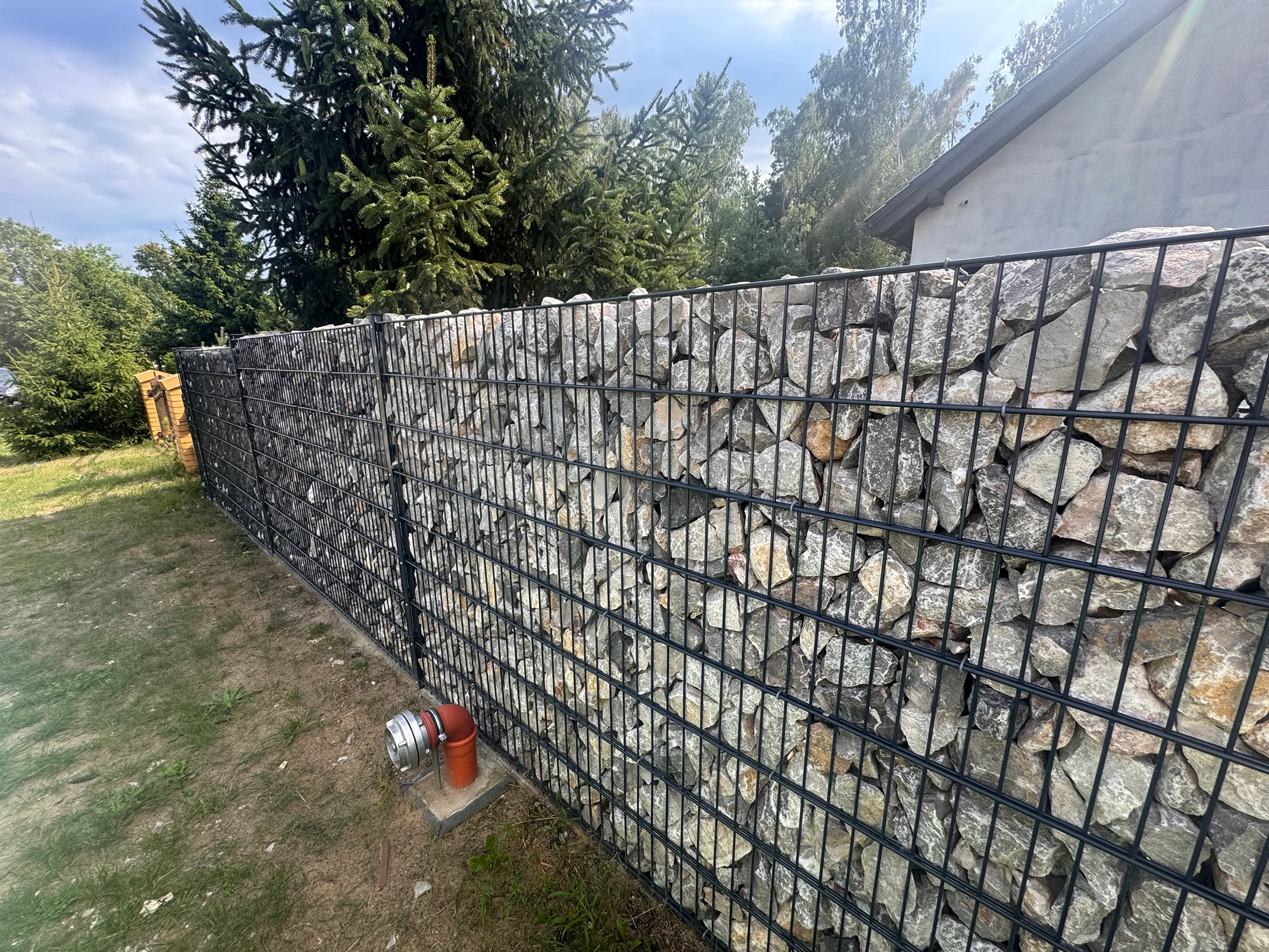 Moderner Metallzaun mit Steinfüllung