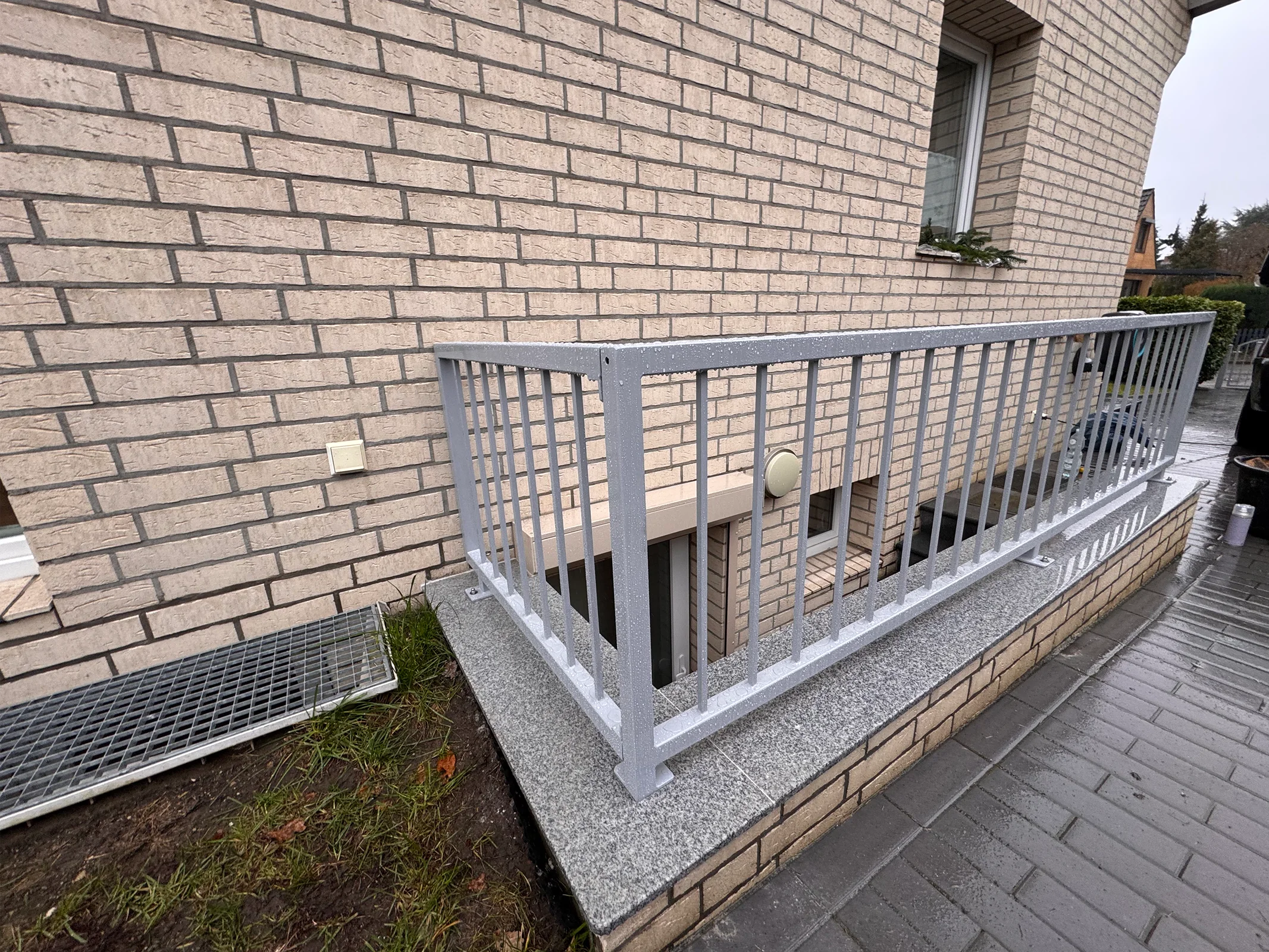 Weißes Metallgeländer am Kellerbereich Backsteingebäude