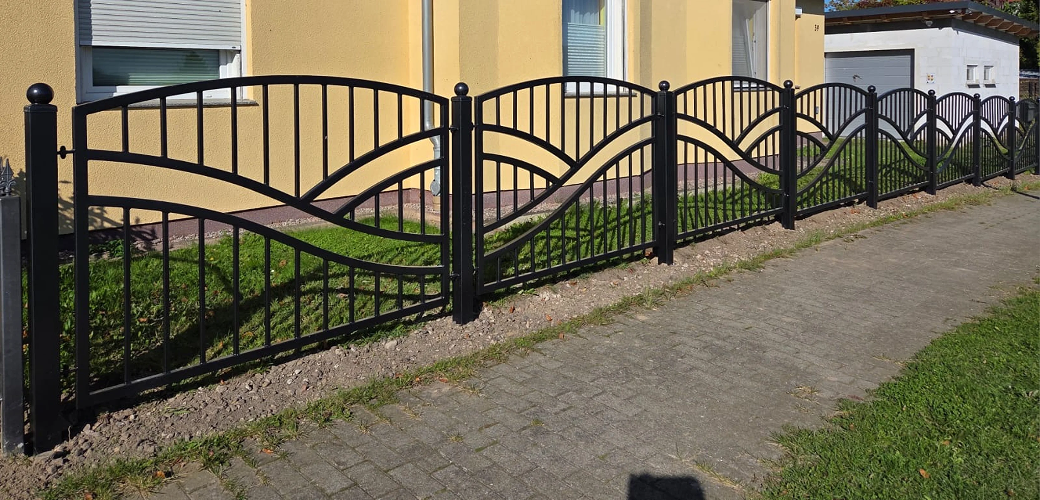 Schwarzes Einfahrtstor mit dekorativem Wellenmuster