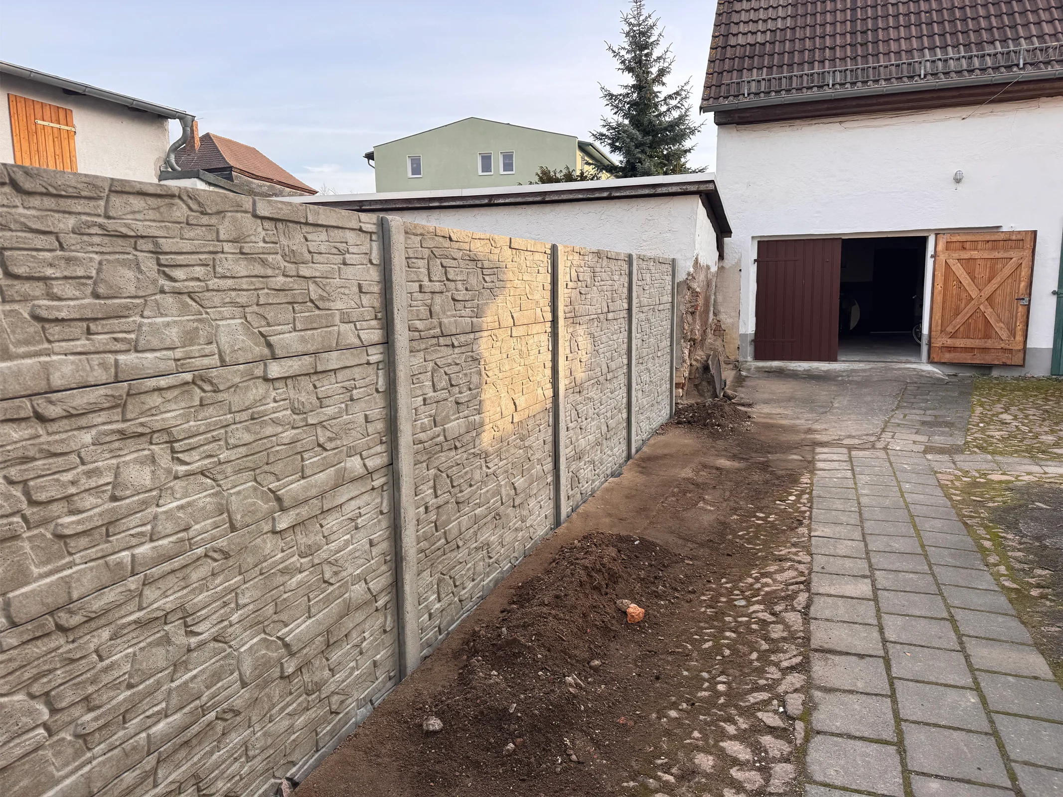 Moderner Betonzaun mit Metallkonstruktion und Hofbelag