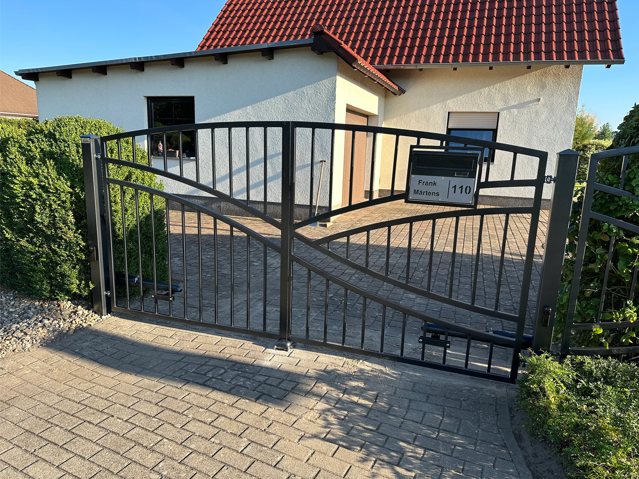 Schwarzes Metallgittertor vor modernem Haus