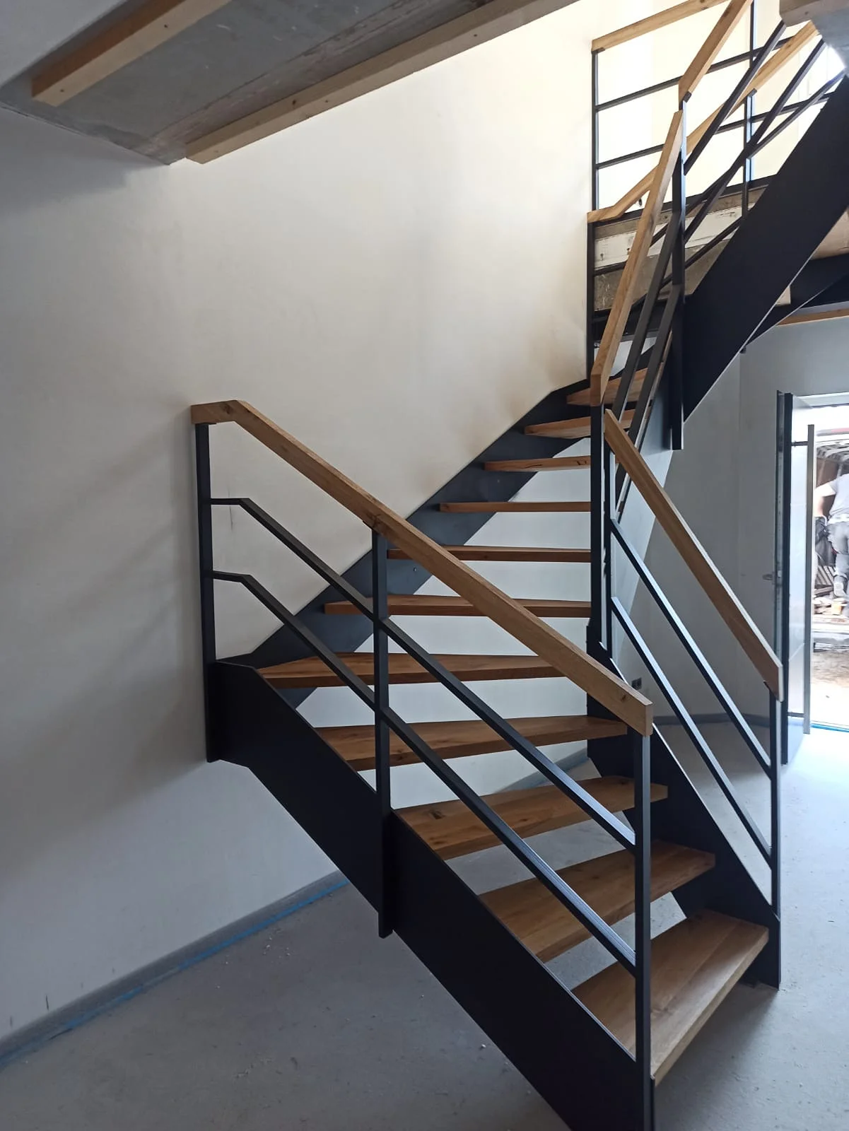 Moderne Treppe mit Stahlgeländer und Holzstufen