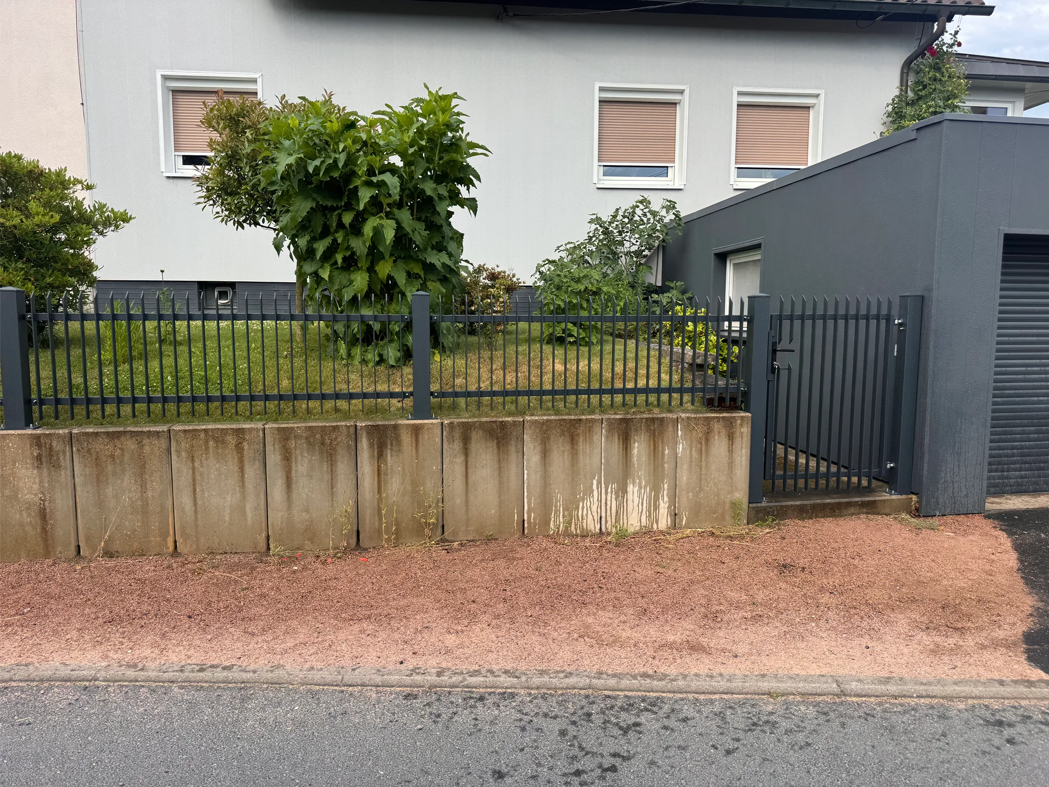 Metallzaun mit Betonunterbau und Tor
