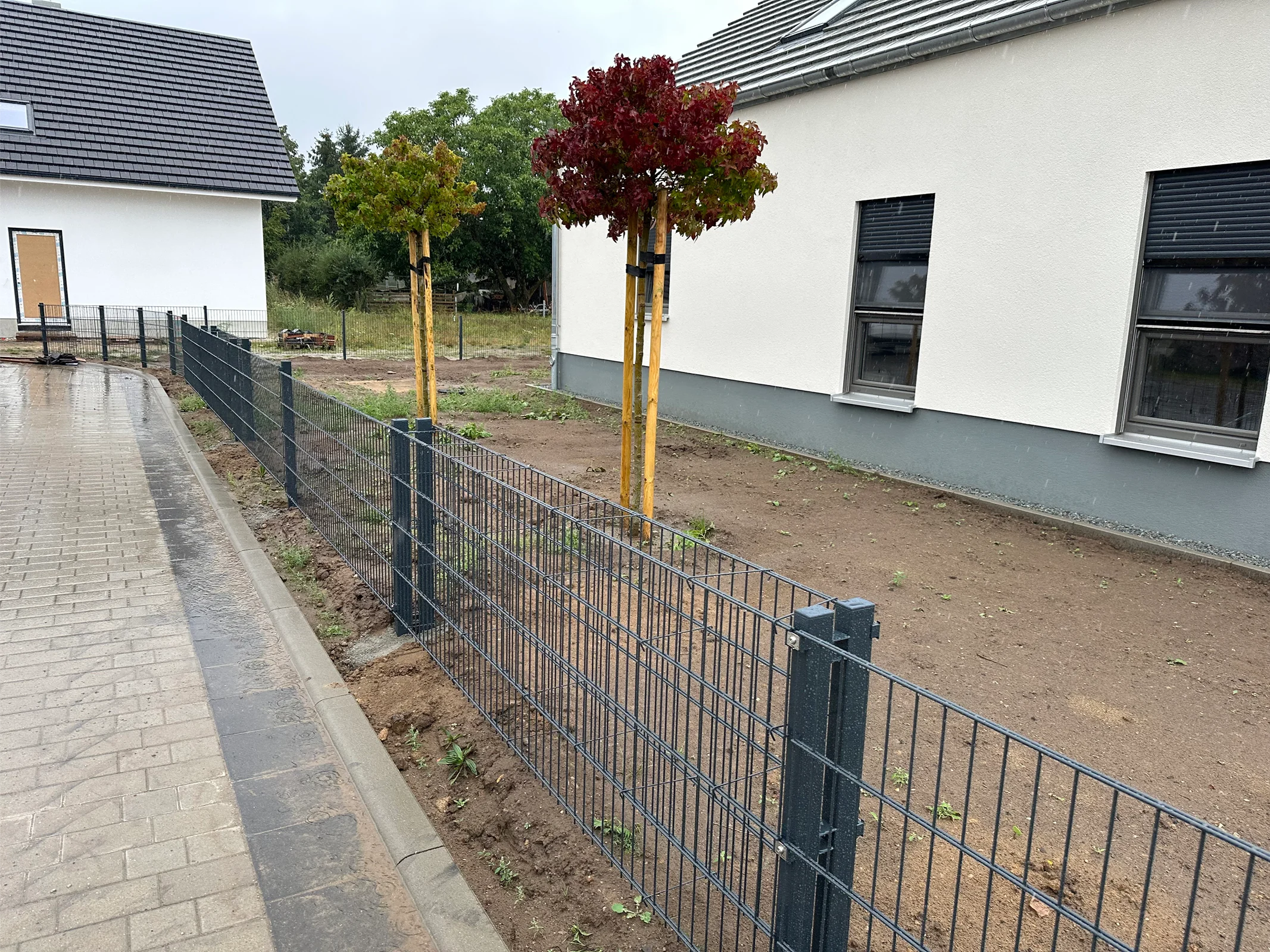 Schwarzer Stahlzaun vor modernem Wohnhaus