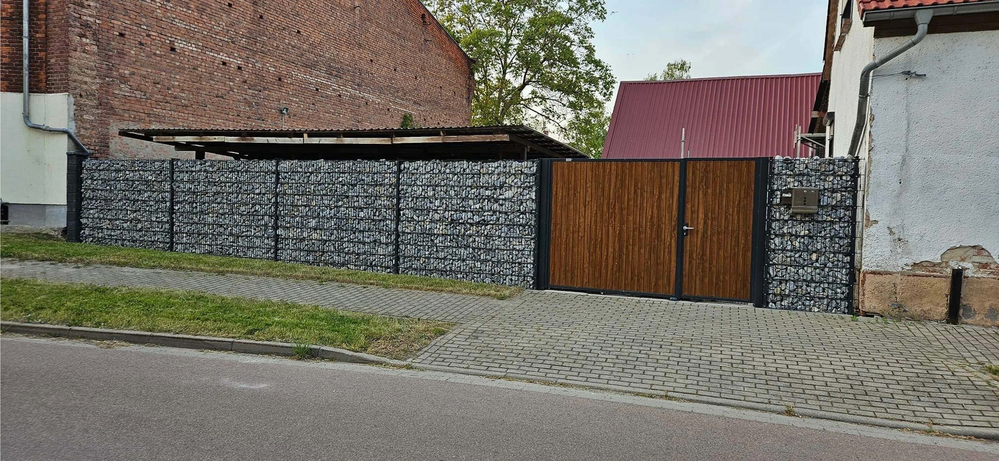 Moderner Zaun mit Steinen und Holztor
