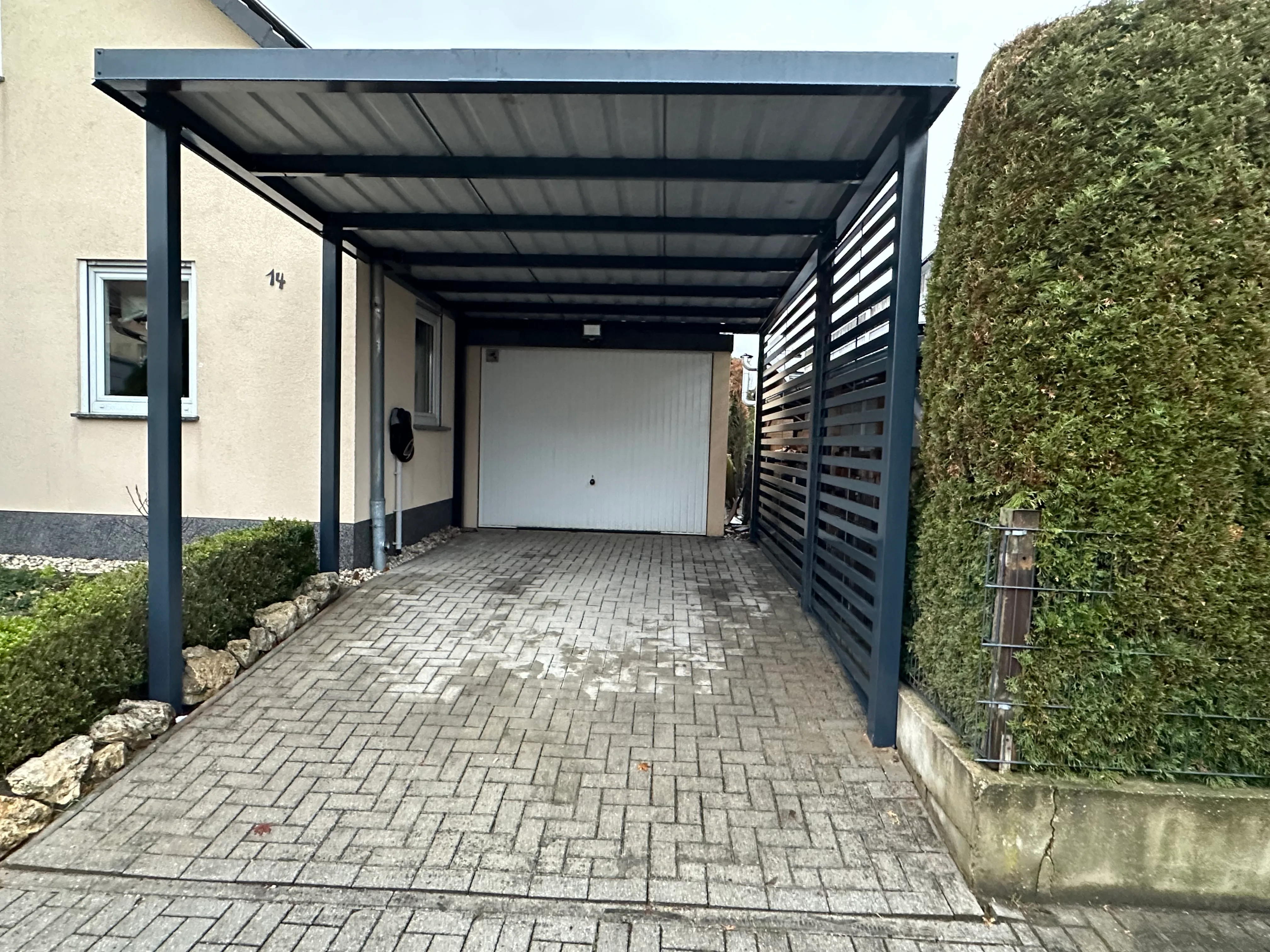 Carport mit Sichtschutz und gepflastertem Boden in modernem Design