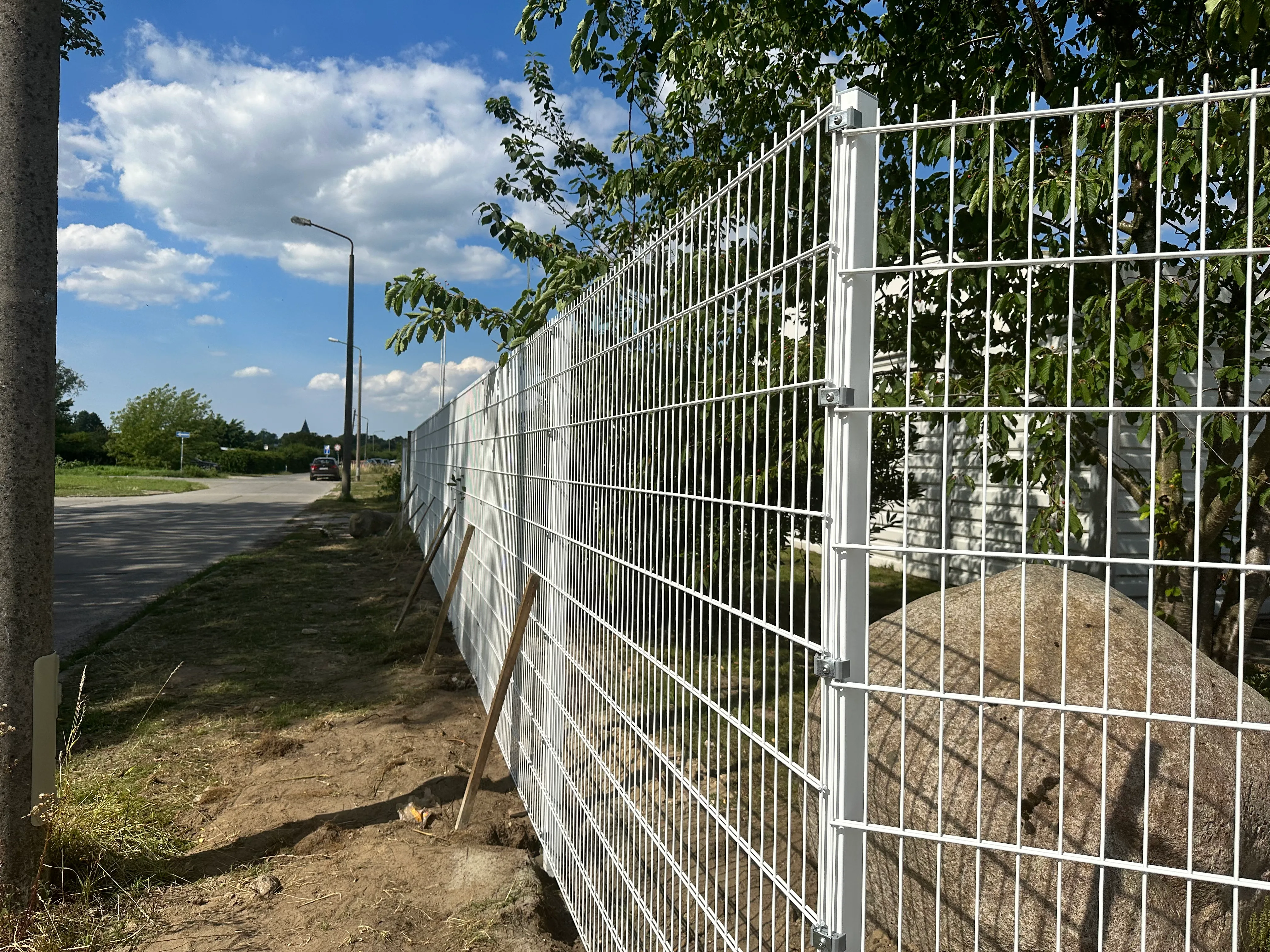 Modernes Zaunsystem in einem Gartenbereich, umgeben von Bäumen und Gras