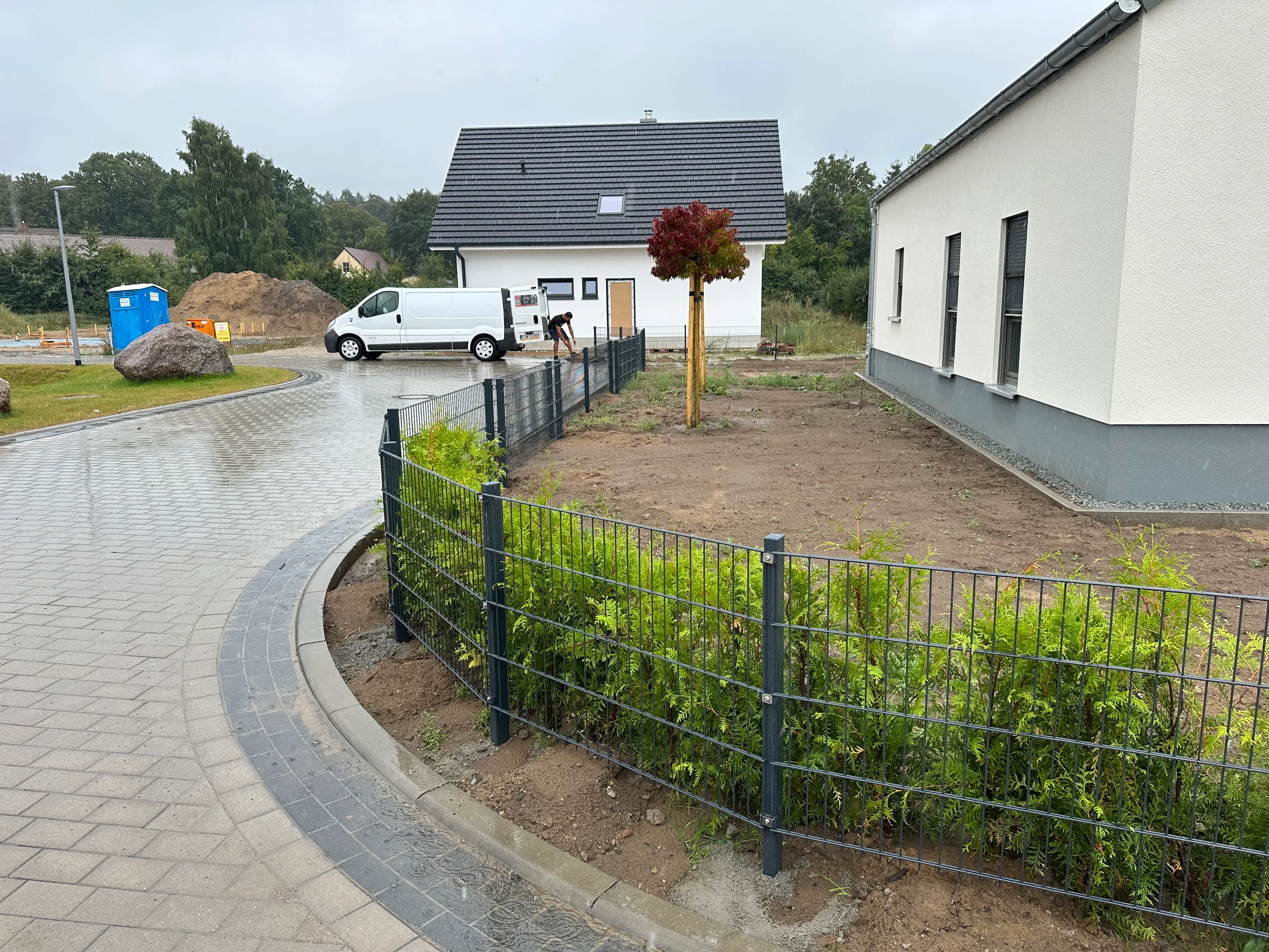 Moderner Zaun aus Doppelstabmatten umschließt den Garten, umgeben von Rasen und Bäumen