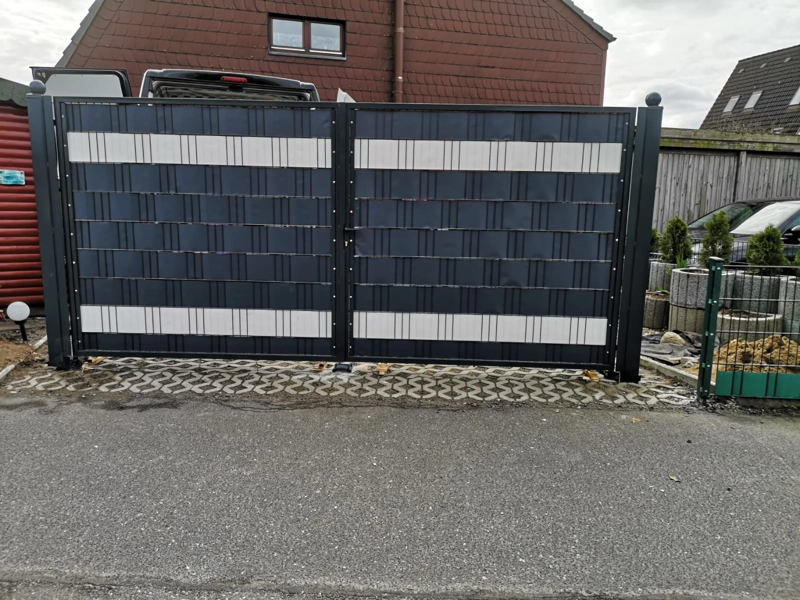 Modernes Gartentor aus hochwertigen Materialien mit zwei Flügeln in dunkler Farbe