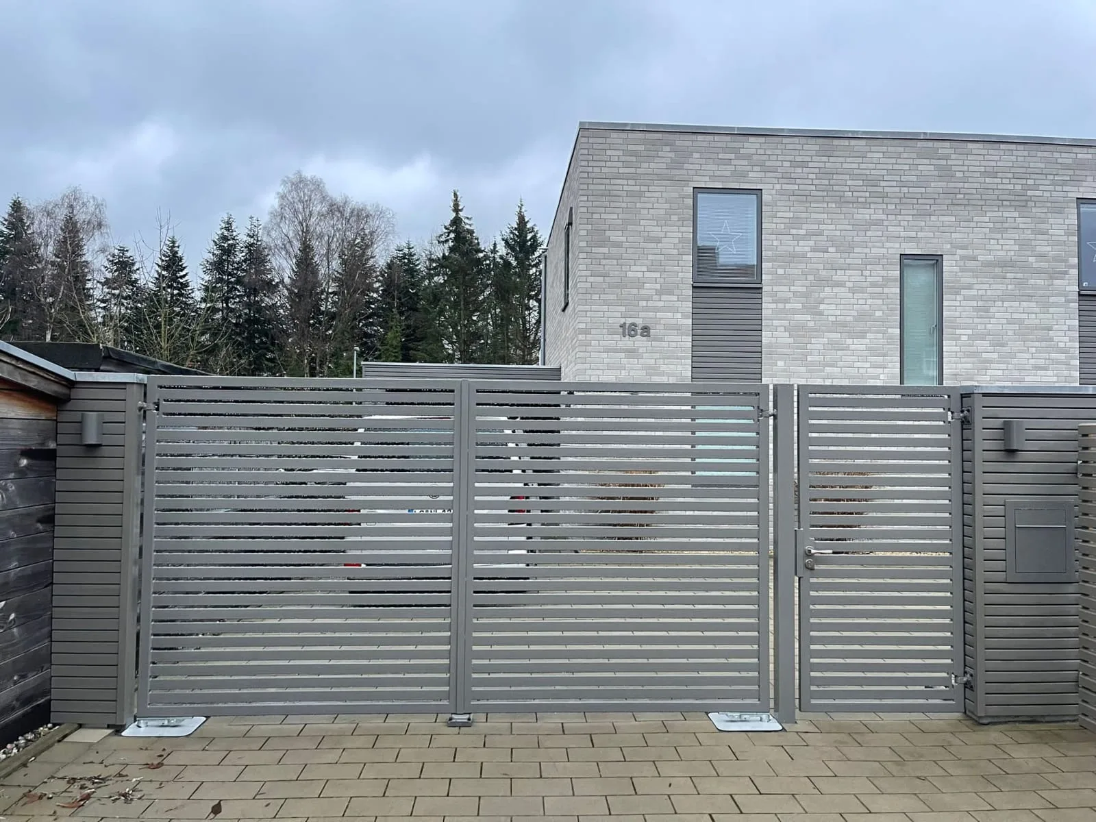 Modernes Schiebetor mit horizontalen Lamellen und elegantem Design vor einem Wohngebäude