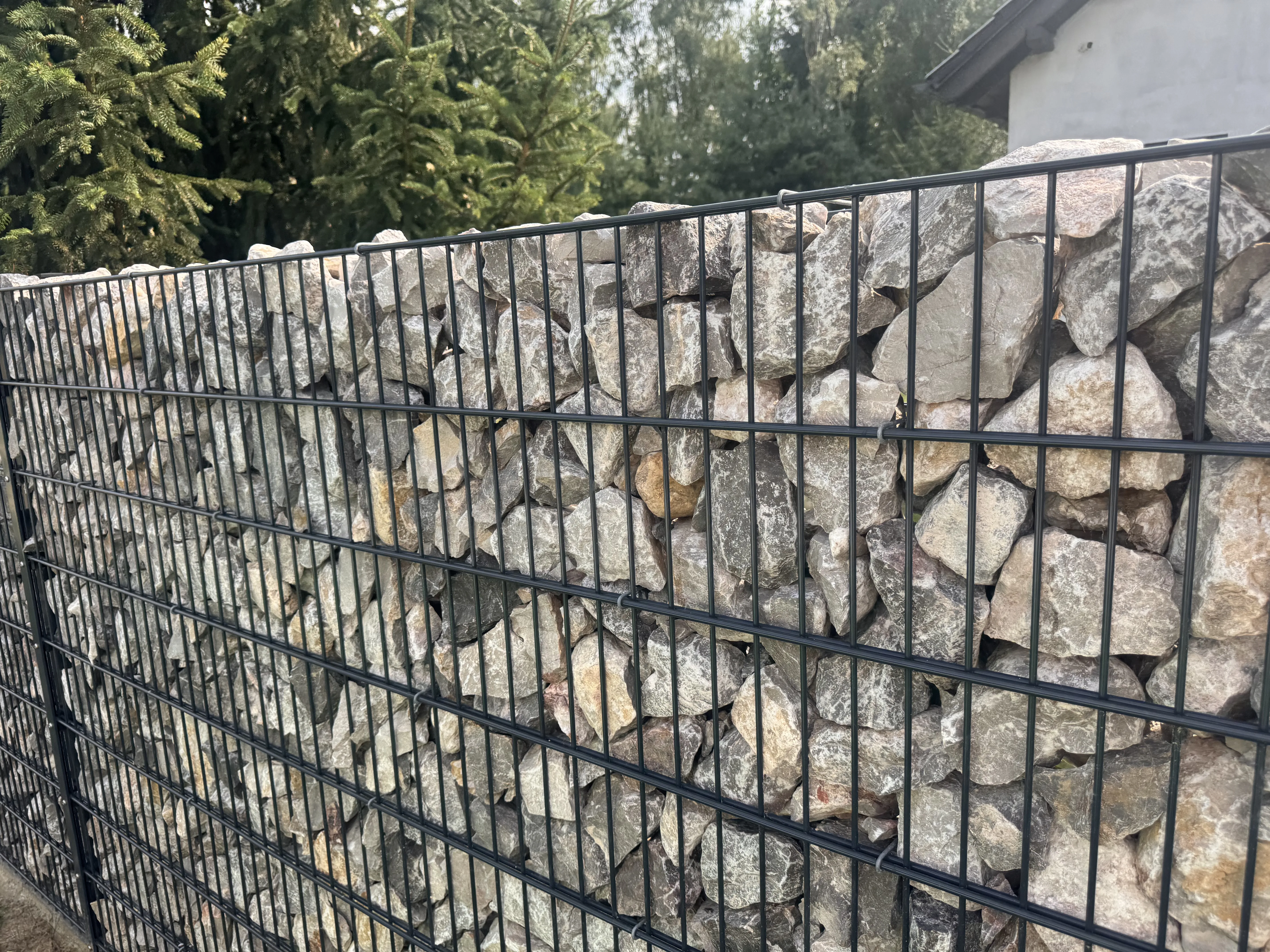 Gabionenzaun mit bruchsteinen in einem modernen Garten
