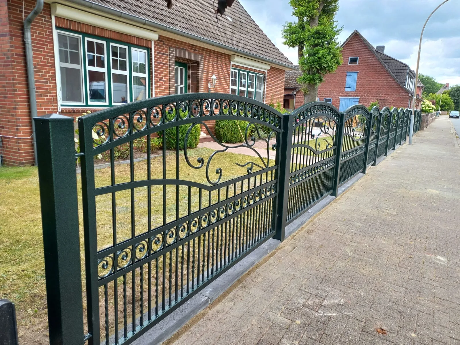Klassischer Zaun mit dekorativen Elementen vor einem Einfamilienhaus