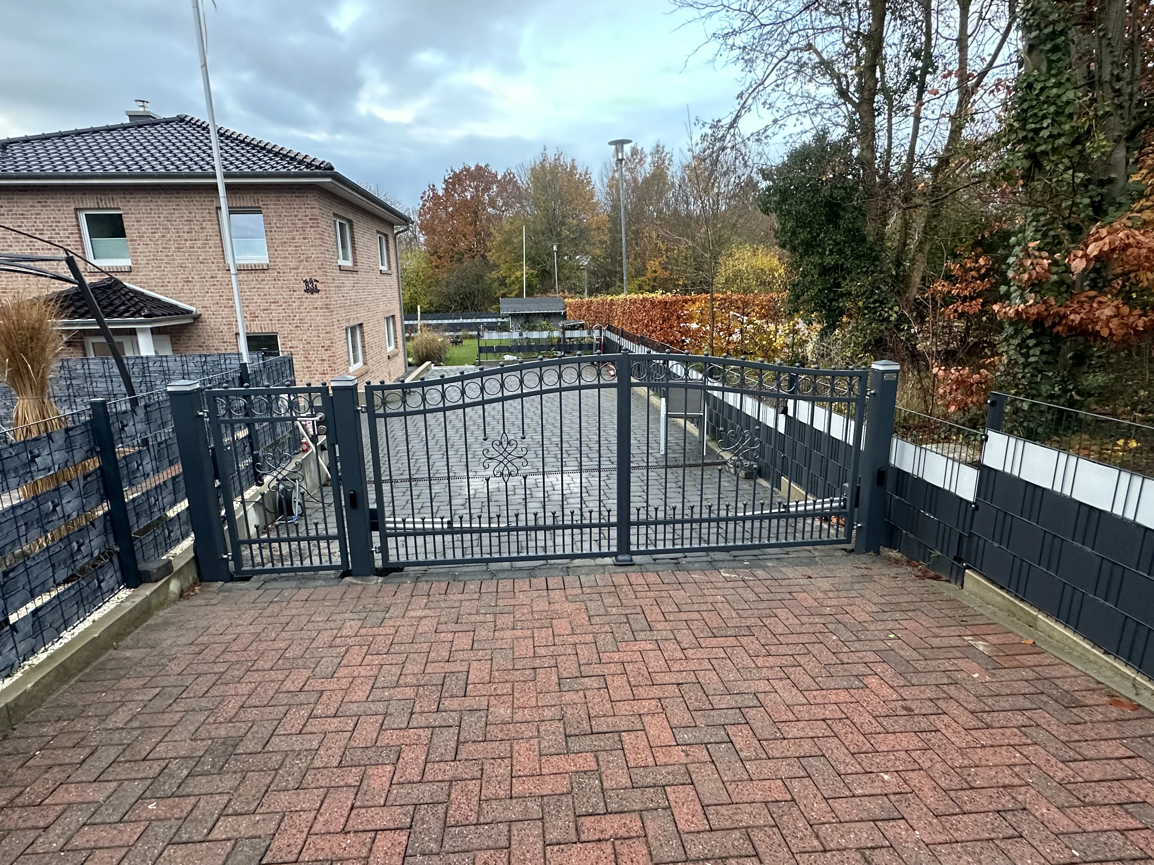 Modernes Gartentor mit Ausblick auf Parkplatz und umliegende Bäume