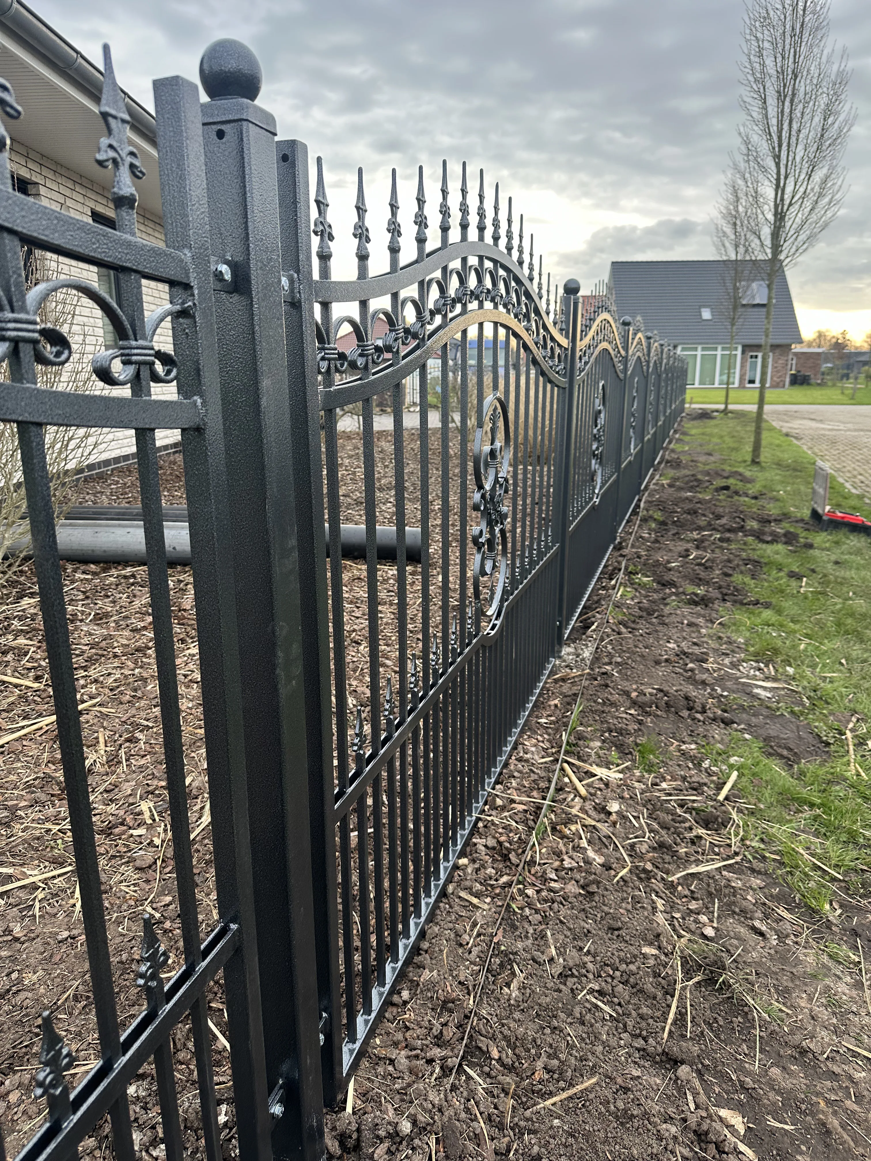 Moderner Metallzaun mit dekorativen Elementen in einem Garten