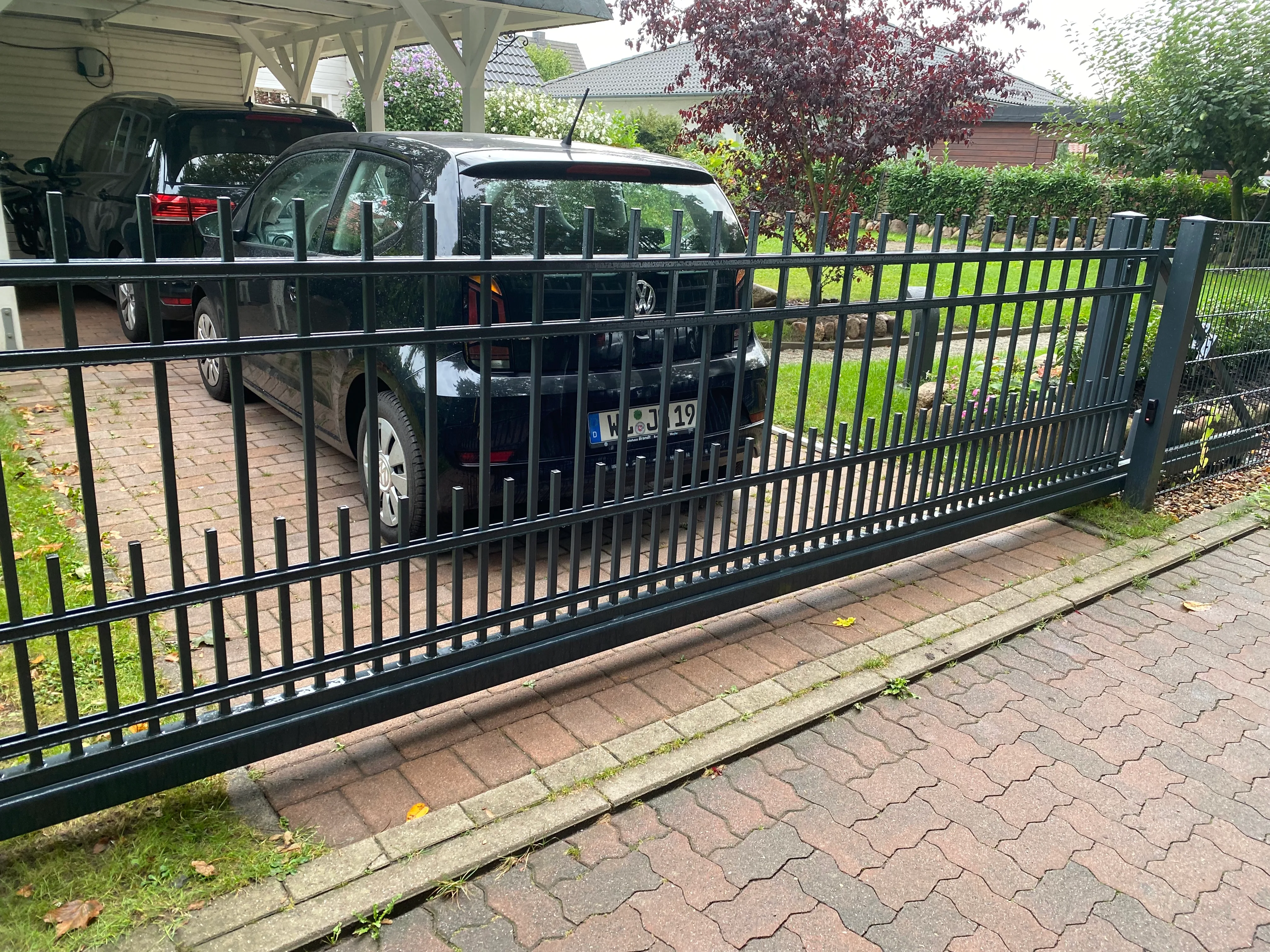 Moderner Zaun mit einem PKW dahinter in einem gepflegten Garten
