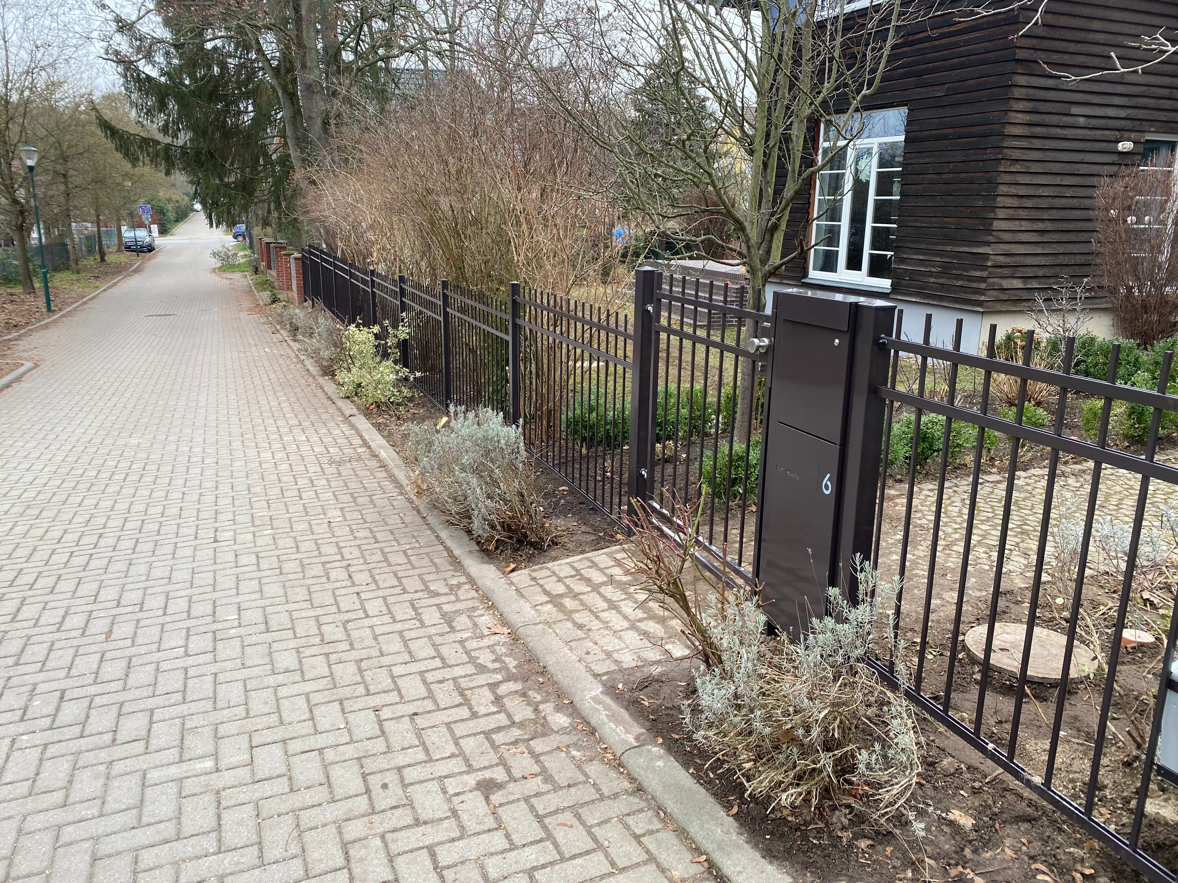 Gartenzaun aus Metall mit modernem Design und Zugangstür zu einem hinteren Bereich