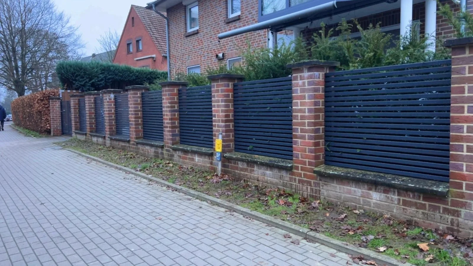 Moderner Sichtschutzzaun aus Holz mit Mauer auf einem Gehweg