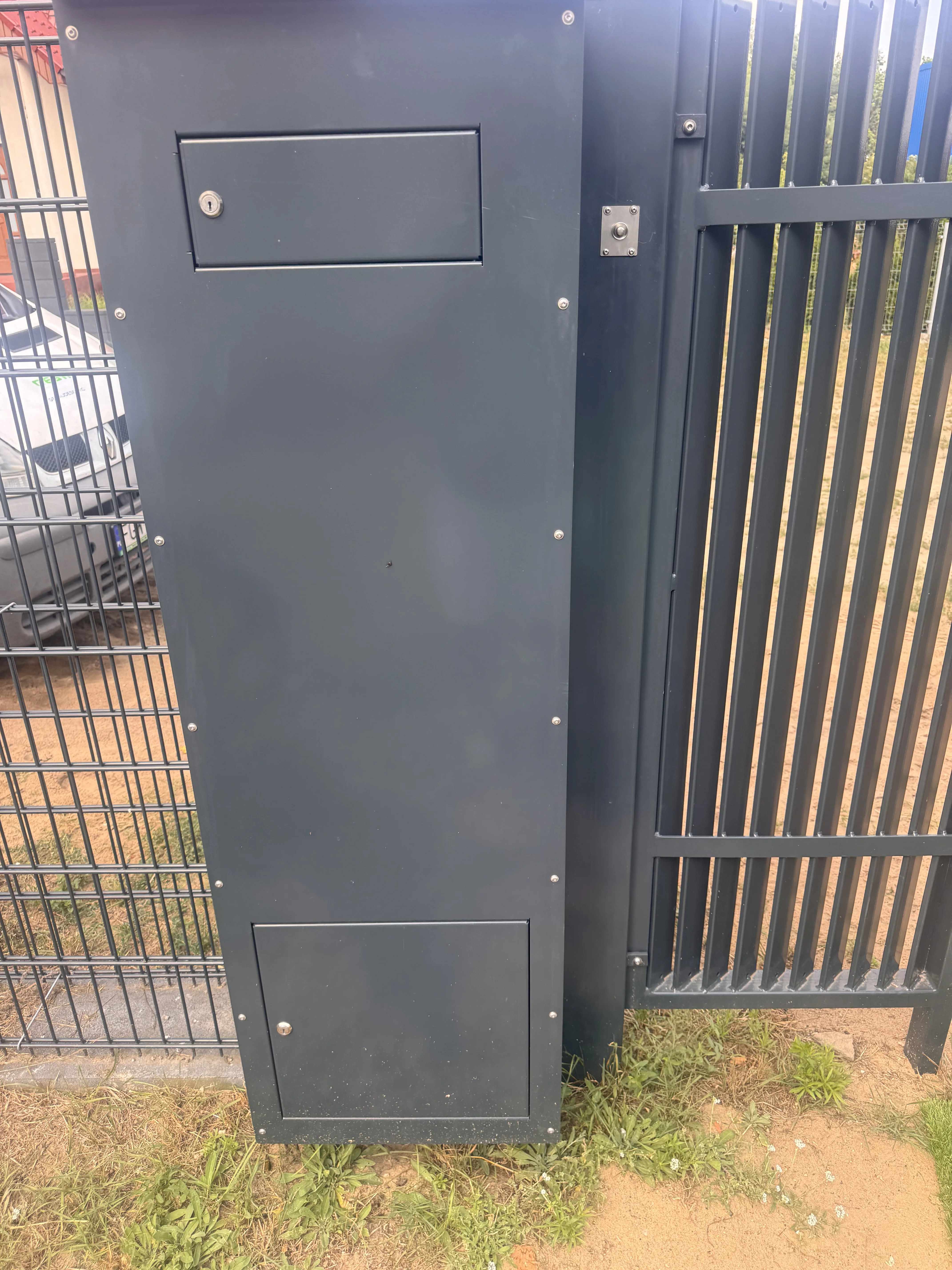 Moderne Zaunanlage mit Briefkasten und Drehtor im Vordergrund