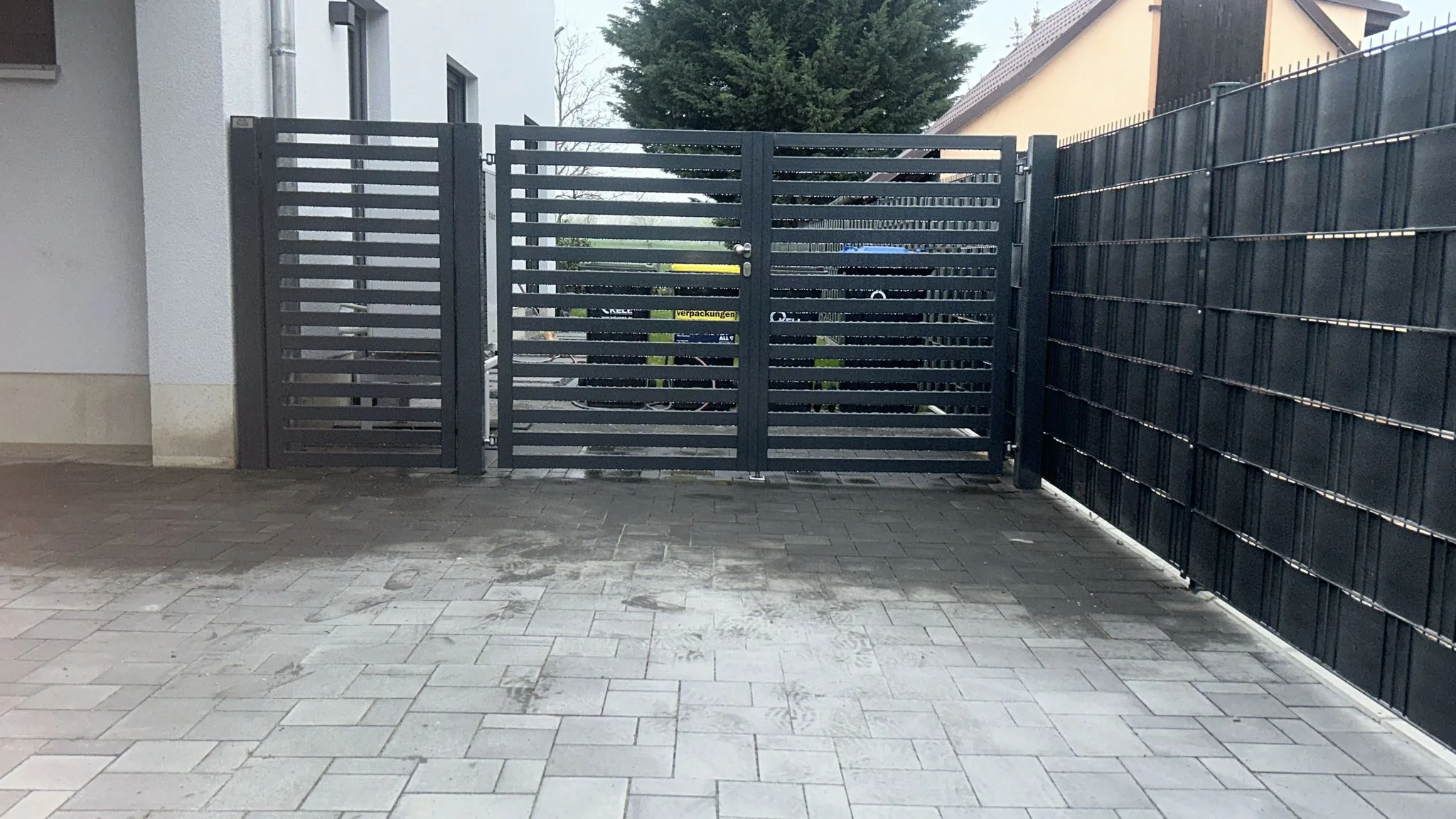 modernes Gartentor aus Metall mit lammellen Struktur und pflegeleichter Umgebung