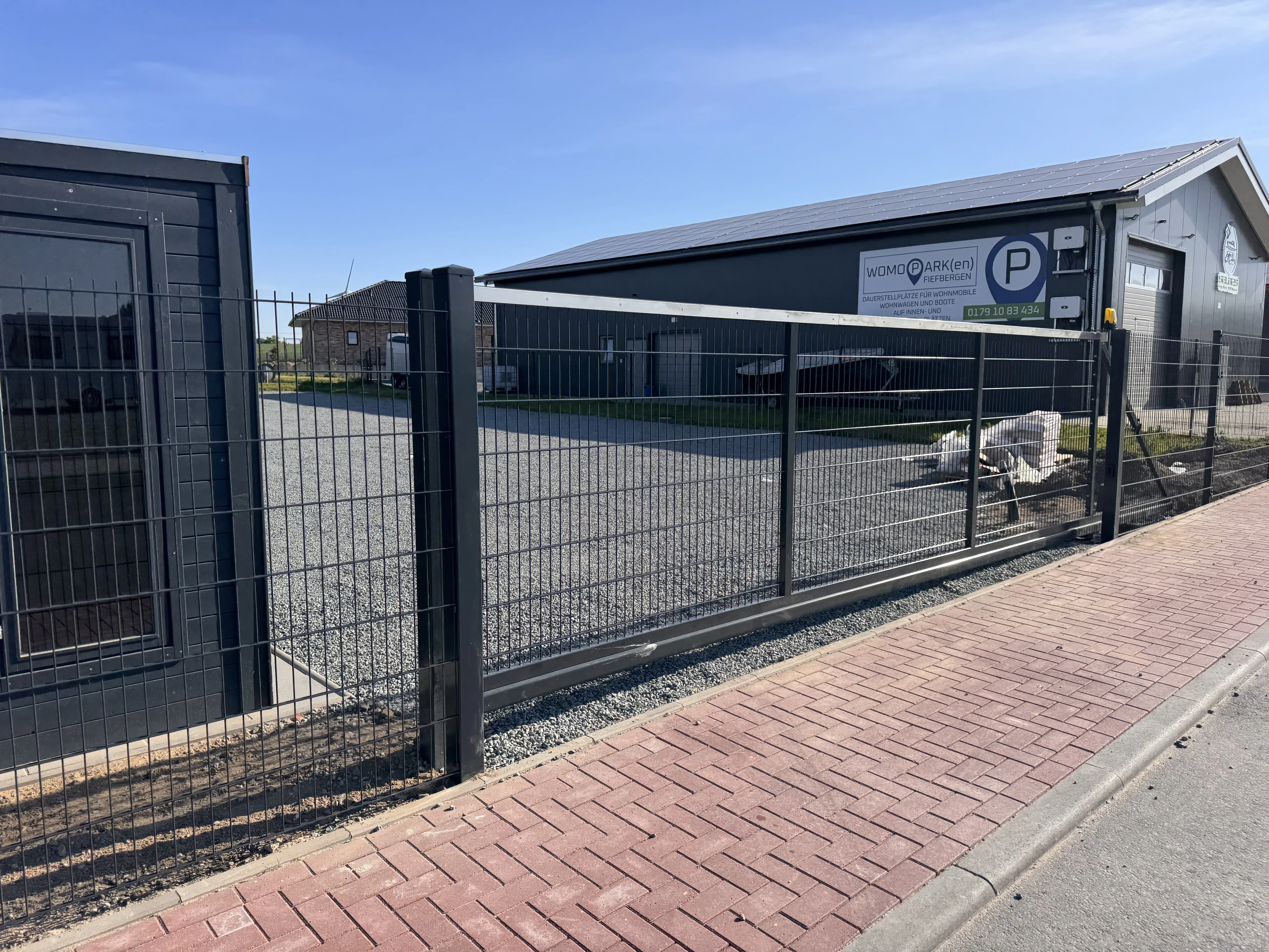 Doppelstabmattenzaun mit modernem Design vor einem Gebäude und Parkplatz