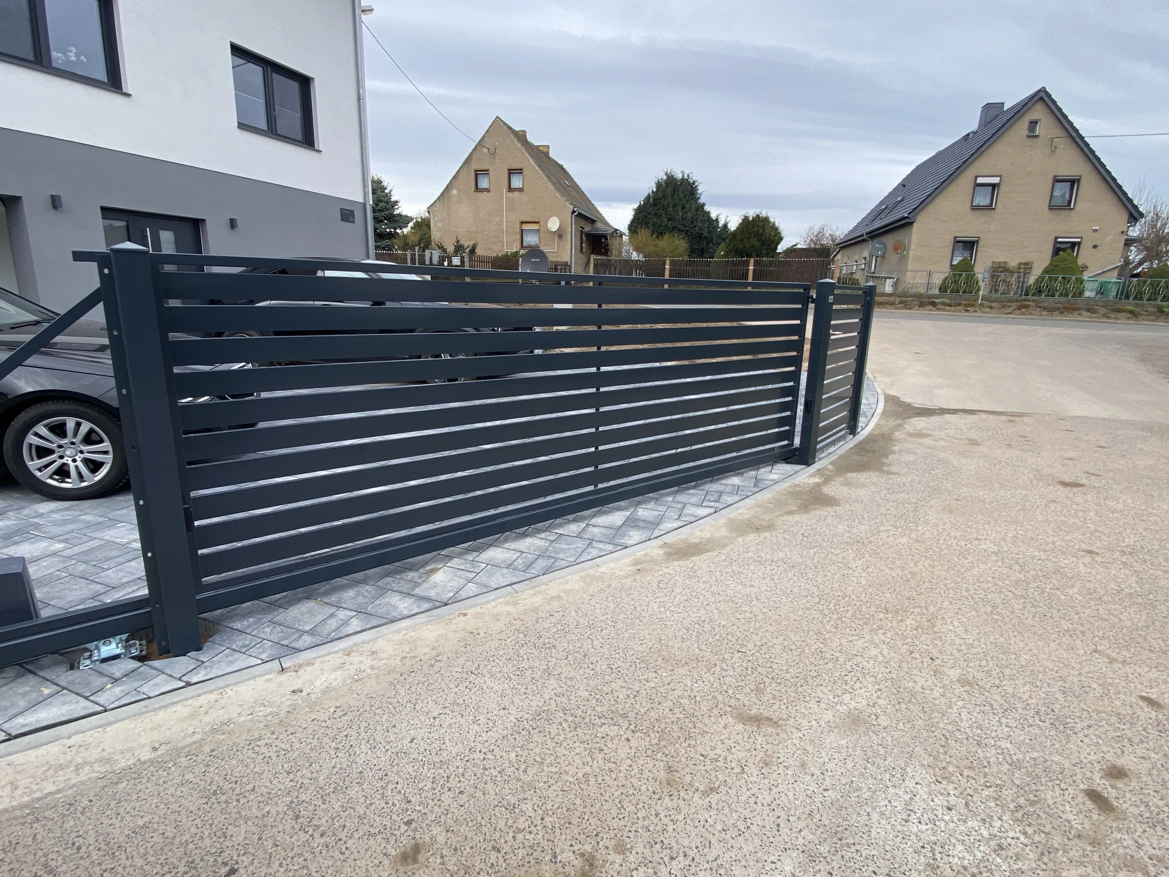 Modernes Gartentor aus Aluminium mit Sichtschutz und Steinpflasterung