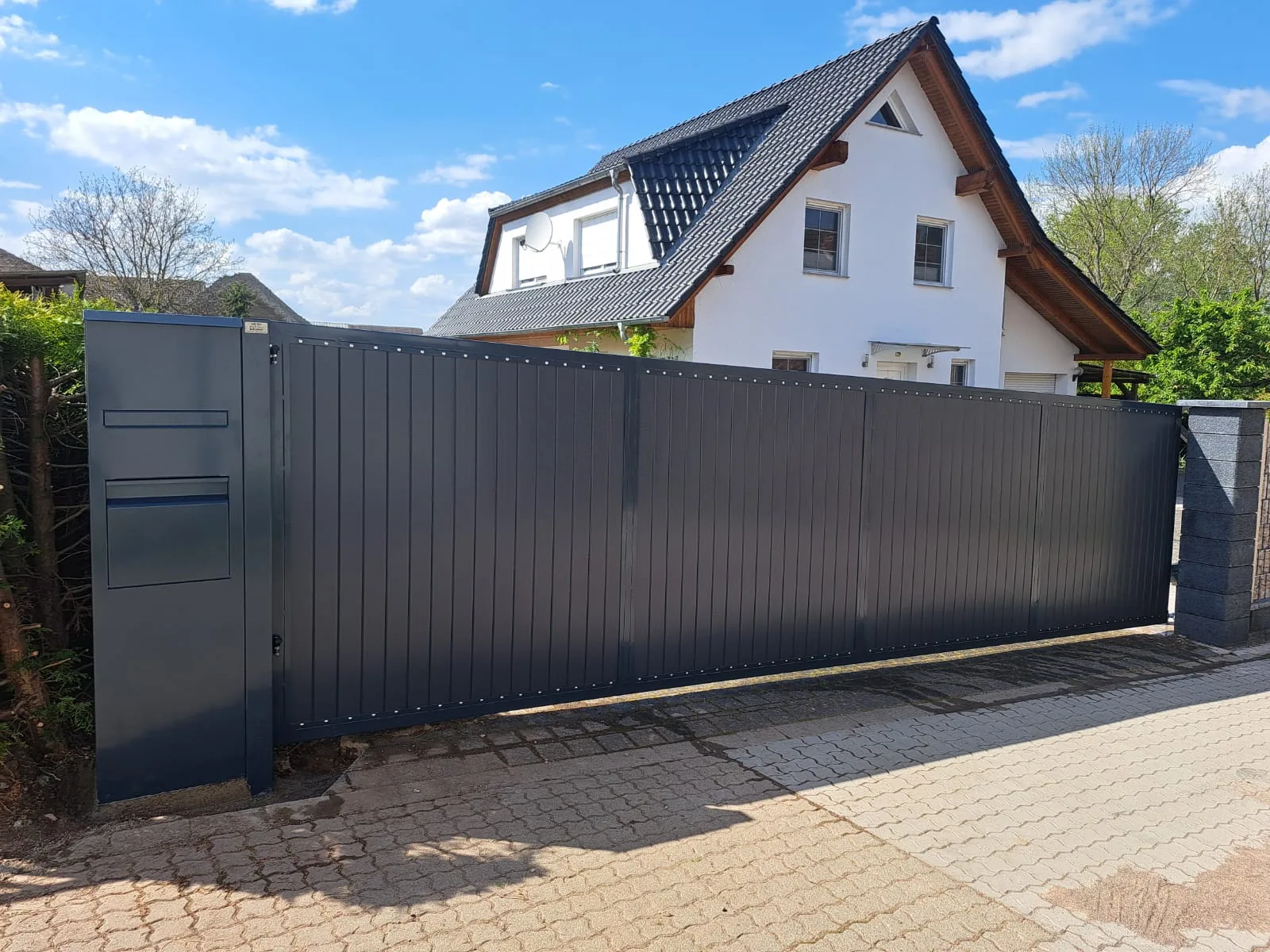 Moderner Zaun mit integrierter Paketbox vor einem modernen Haus