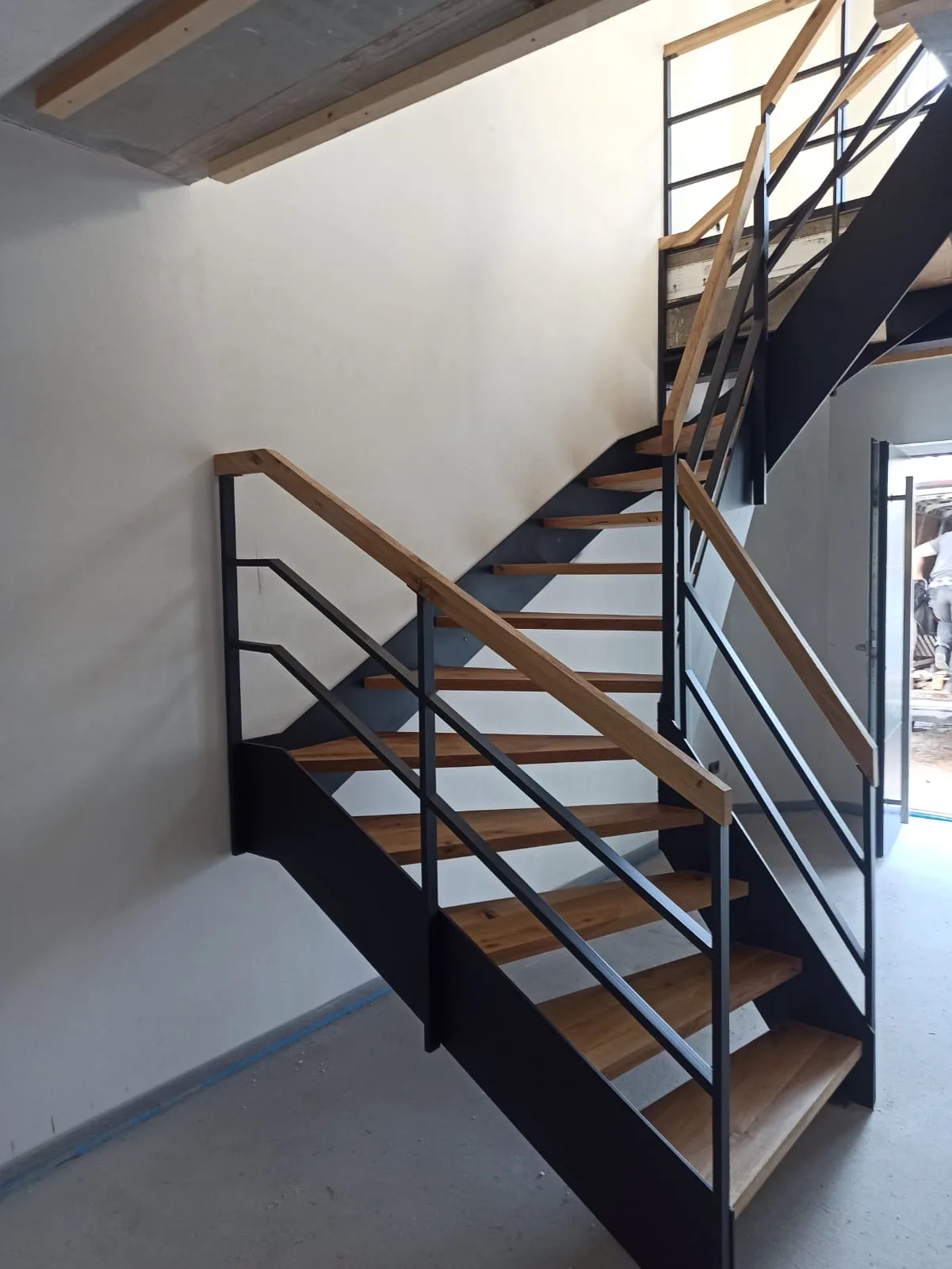 Stahltreppe mit Holzgeländer in modernem Design, gut beleuchtet