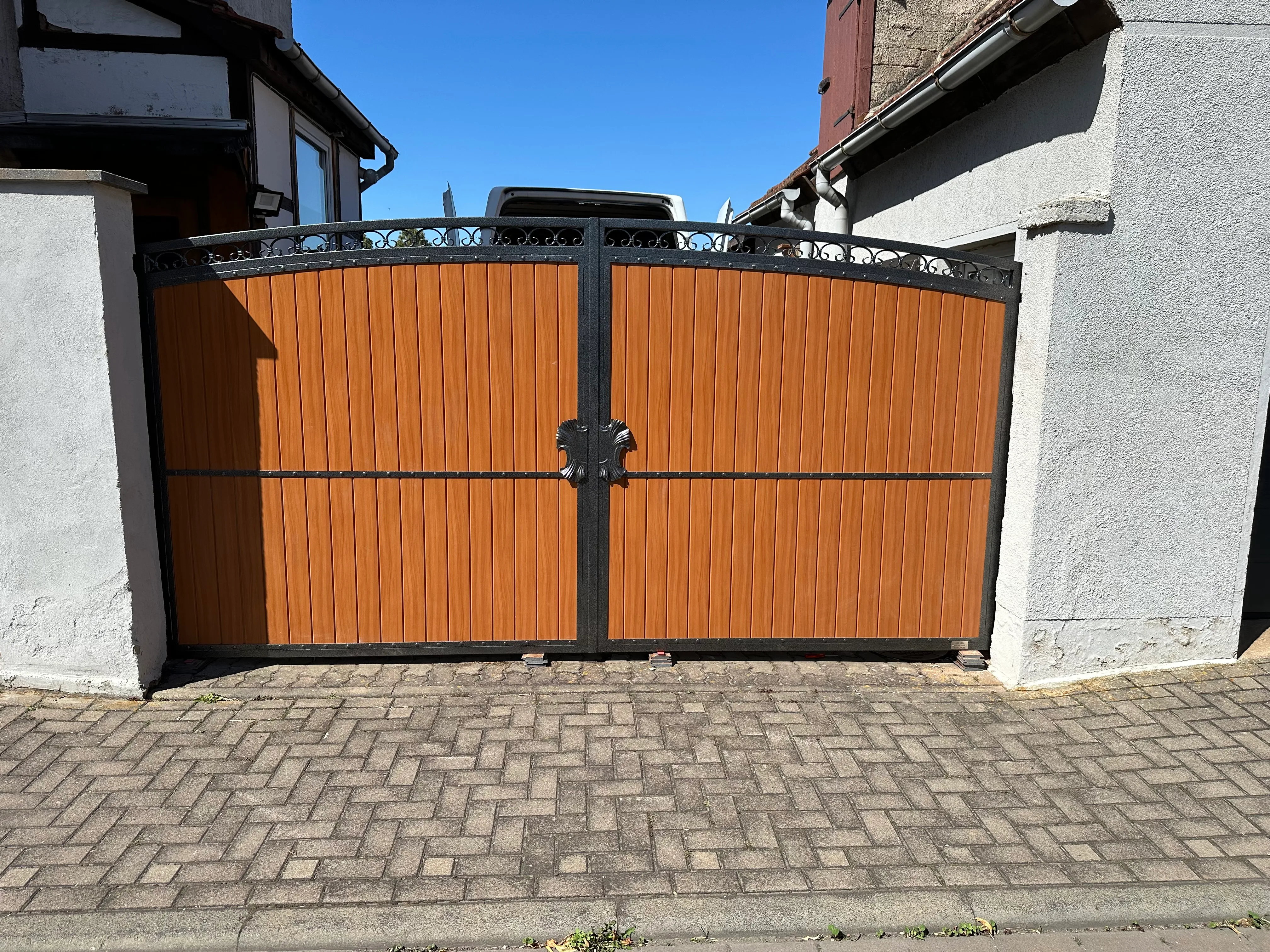 Elegante Holz-Gartentore mit schwarzem Metallrahmen und Mauerwerk im Hintergrund